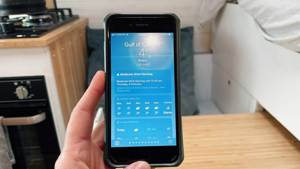 Checking the weather conditions on phone in campervan